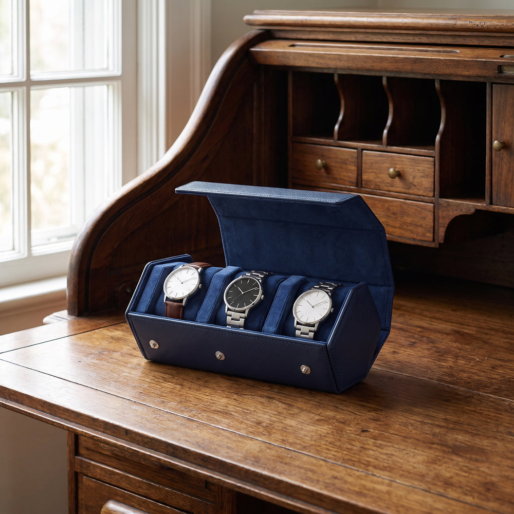 Écrin de voyage Sillage bleu 3 places ouvert et garni de montres, posé sur un bureau secrétaire ancien en noyer