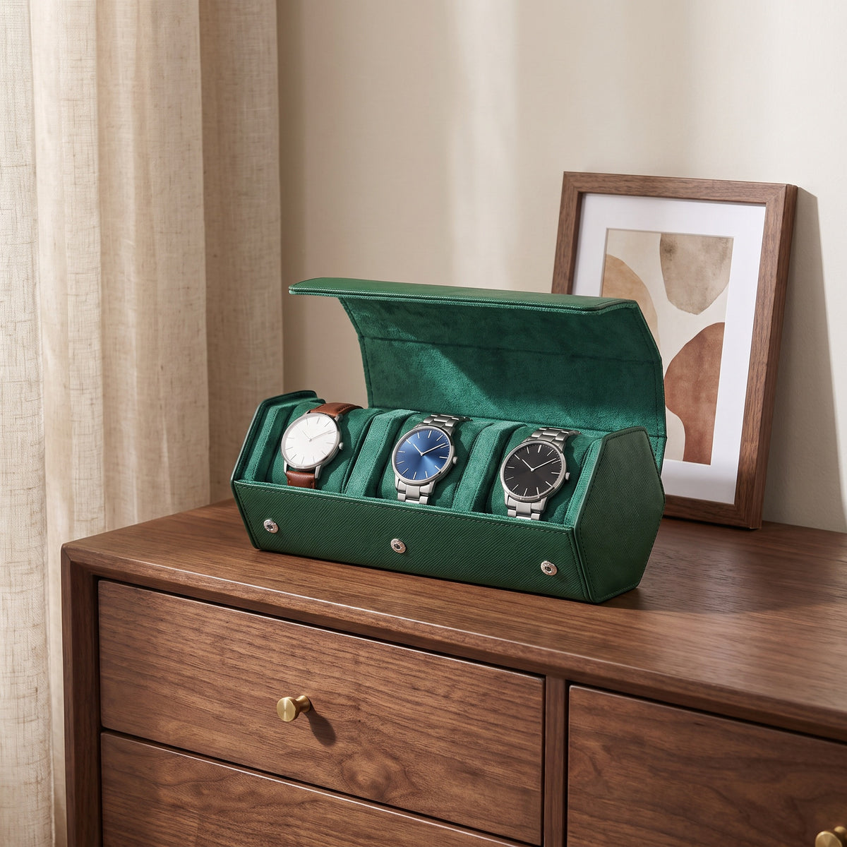 Écrin de voyage Sillage vert 3 places ouvert et garni de montres, posé sur une commode en noyer