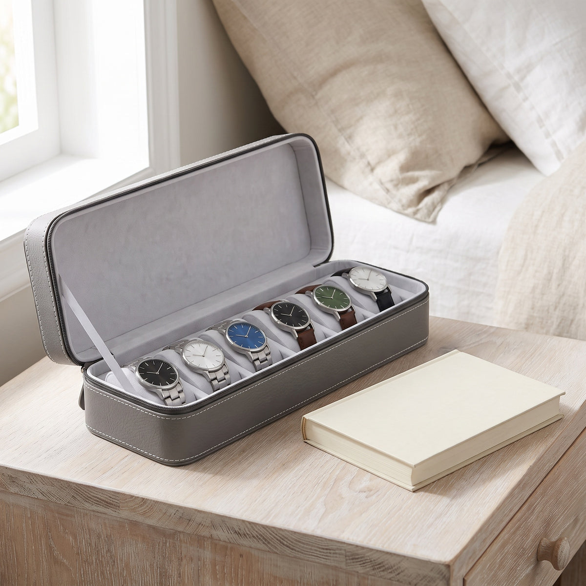 Étui de voyage pour 6 montres Voyageur gris ouvert, posé sur une table de chevet en chêne blanchi