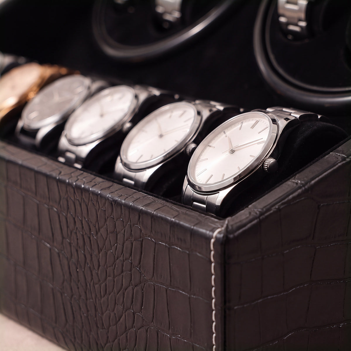 Gros plan sur le plateau du remontoir Héritage croco noir, montres sur leurs coussins et coutures blanches